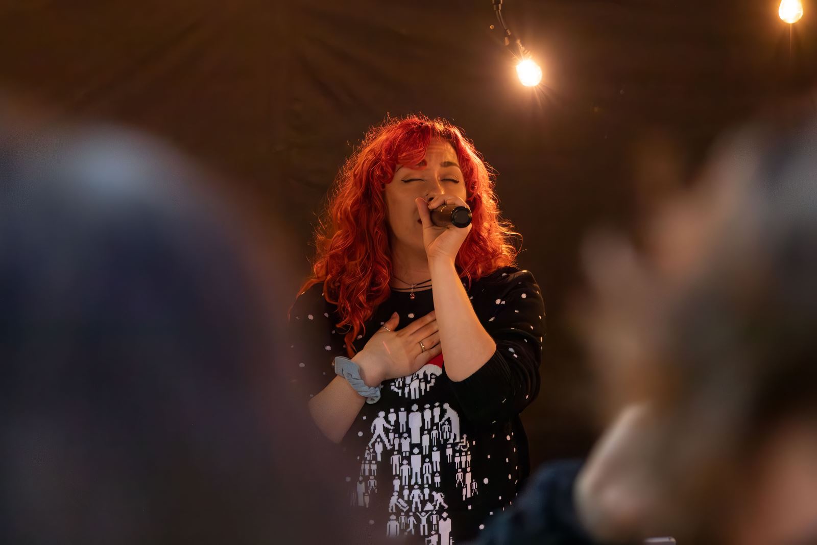 Lady with red hair singing with a microphone